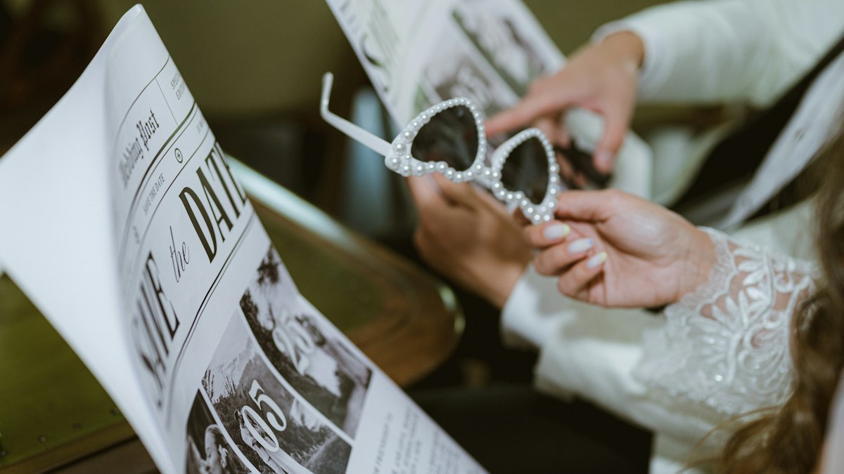 Brautpaar mit Sonnenbrille hält eine Zeitung in den Händen