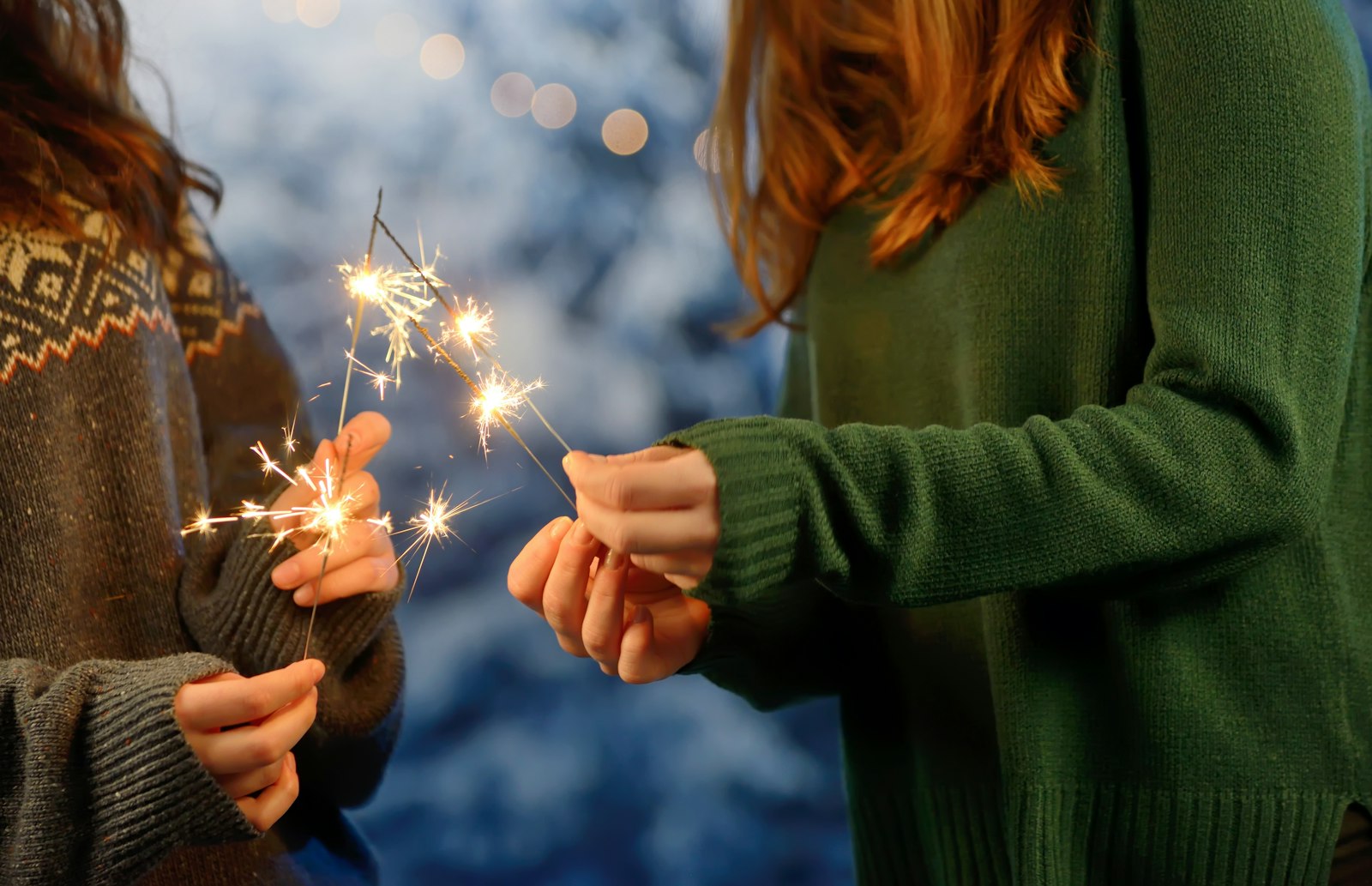 Zwei Frauen halten nachts Wunderkerzen, die ihre Gesichter beleuchten
