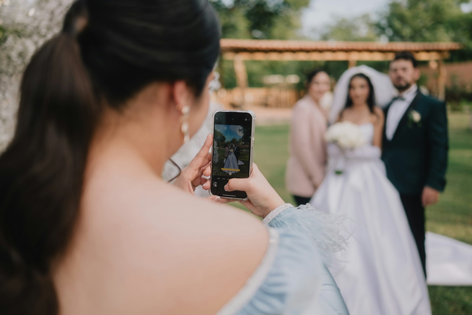 Hochzeitsgast fotografiert das Brautpaar mit dem Smartphone