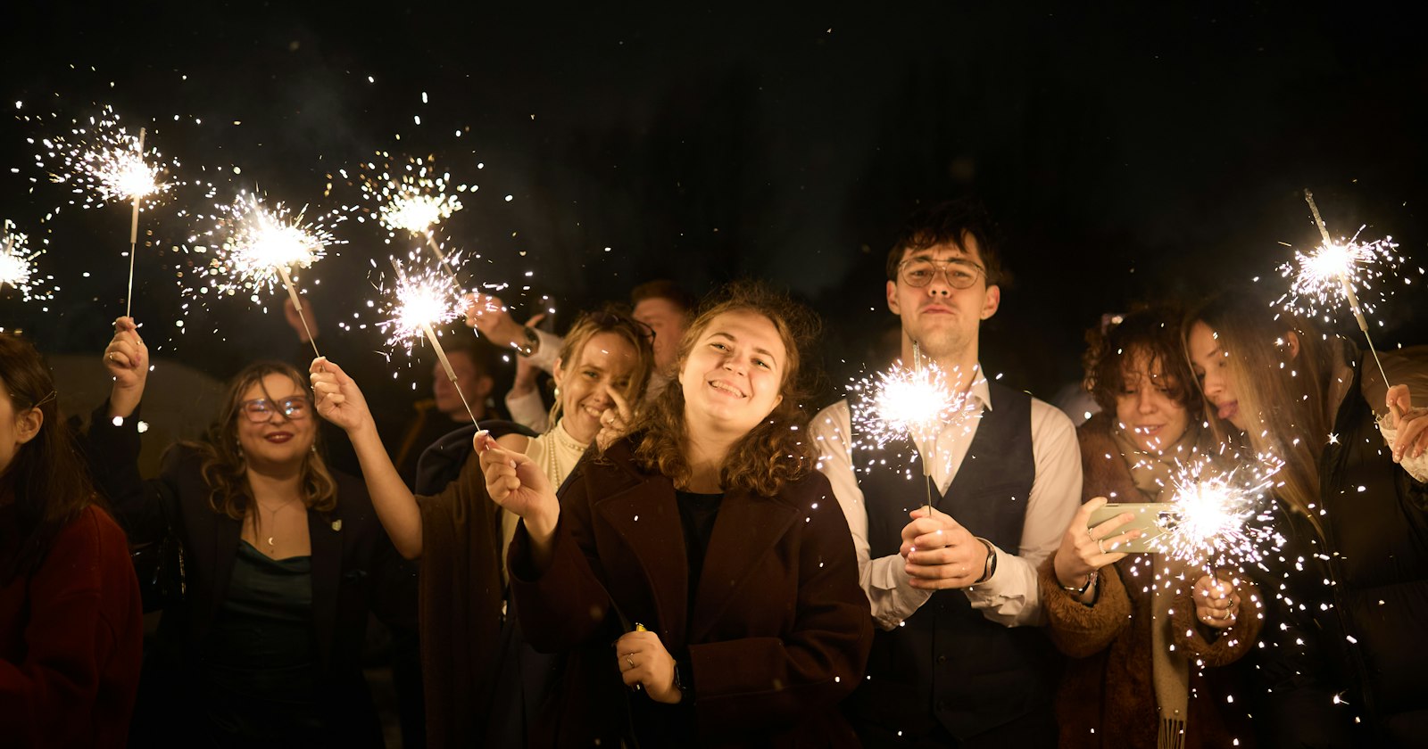 Freunde feiern nachts mit leuchtenden Wunderkerzen