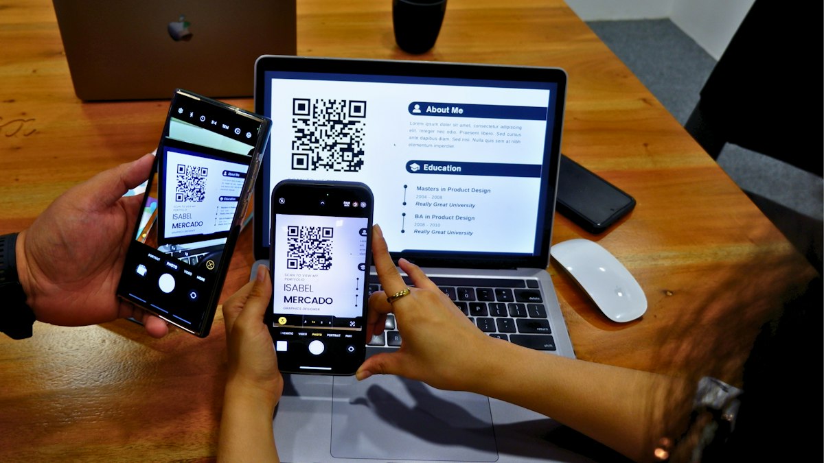 Zwei Personen am Tisch scannen einen QR-Code mit dem Handy