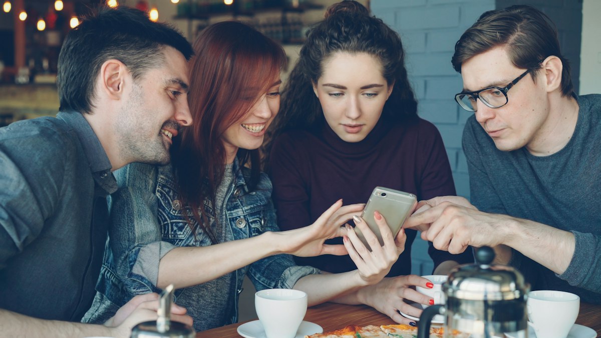 Freunde schauen sich gemeinsam Fotos auf einem Smartphone an