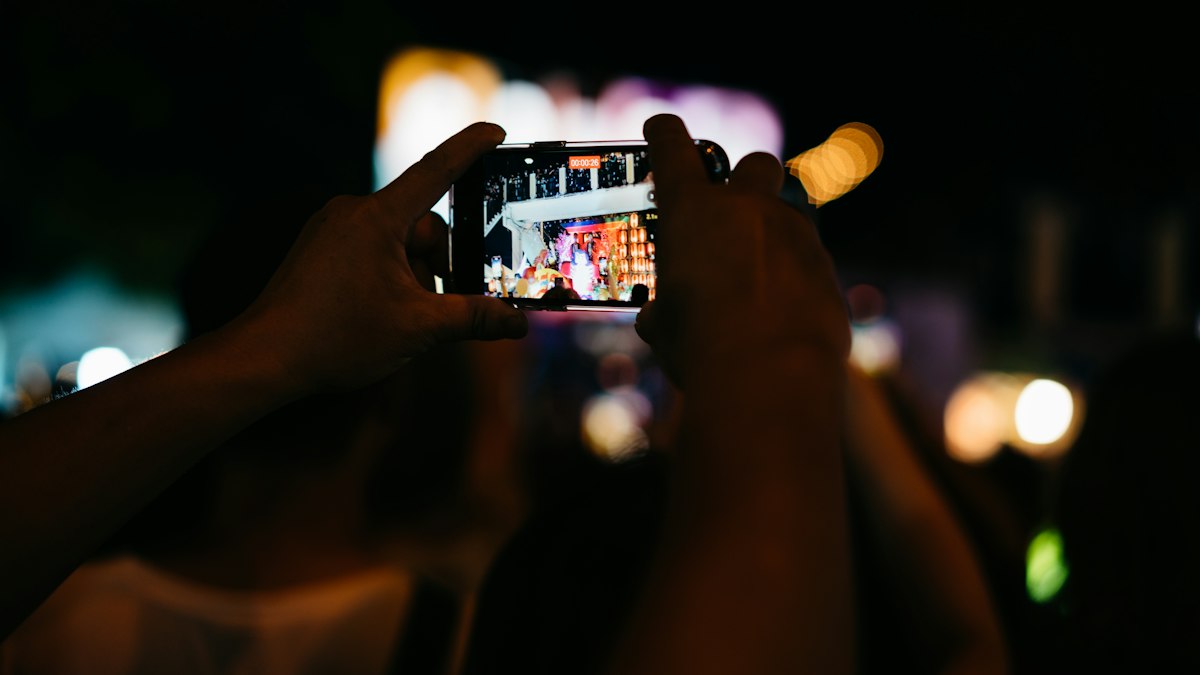 Person fotografiert mit dem Smartphone in einem dunklen Raum