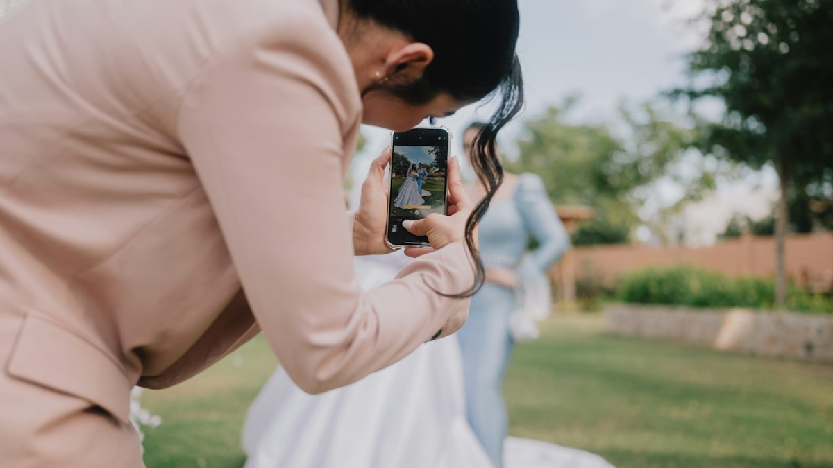 Hochzeitsgast fotografiert die Braut im Freien