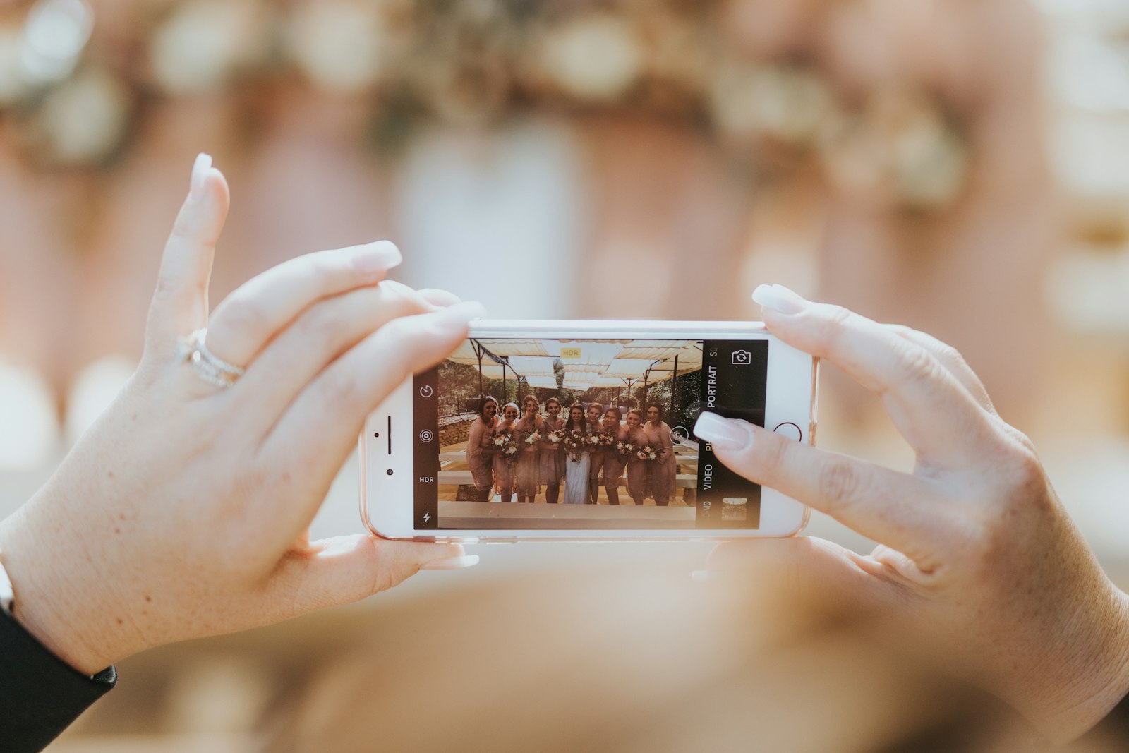 Eine Person hält ein Smartphone hoch und fotografiert eine lachende Gruppe von Frauen